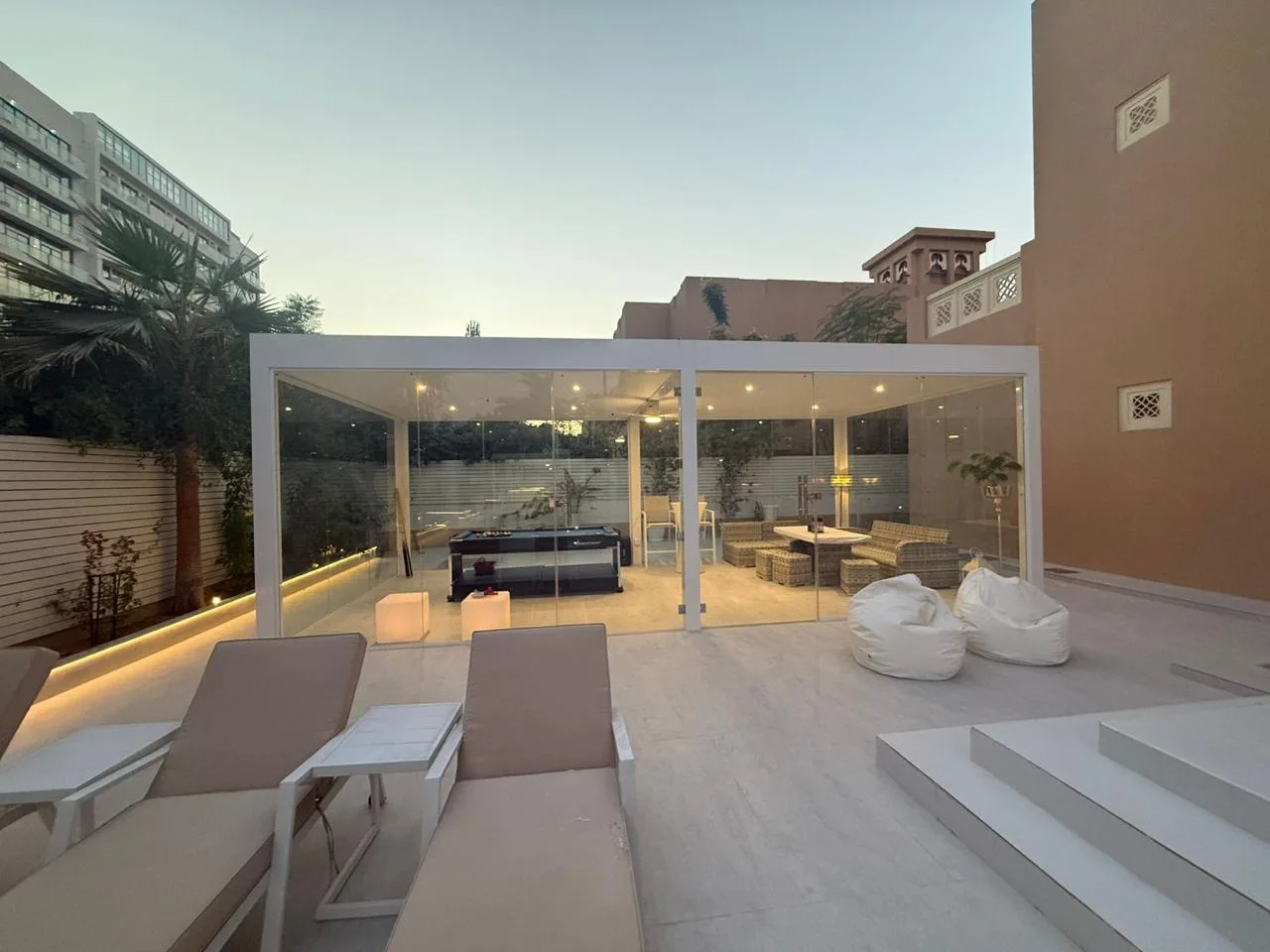 Glass aluminium pergola lounge with LED lighting at dusk