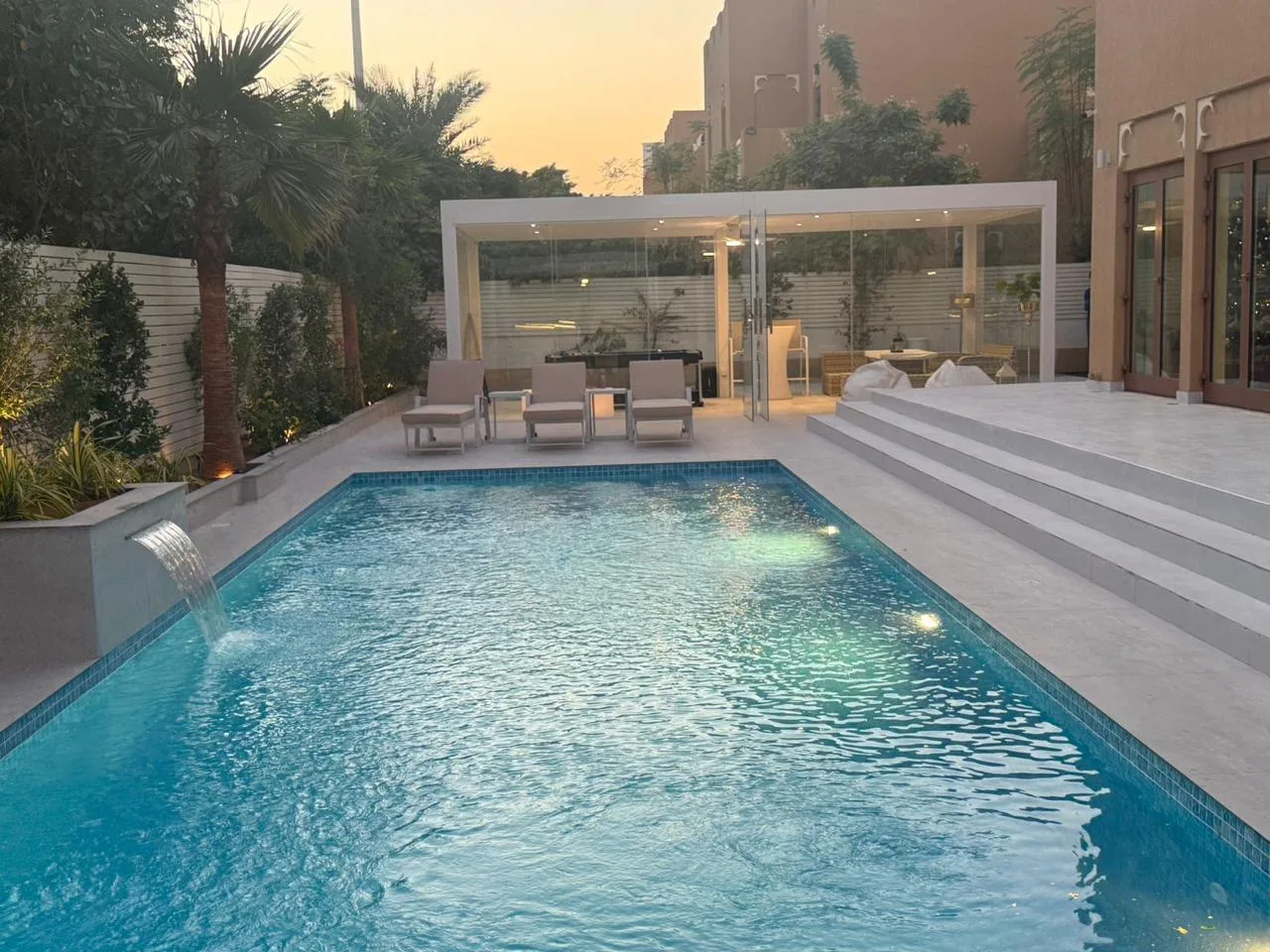 Aluminium pergola poolside cabana at sunset with water feature, Dubai